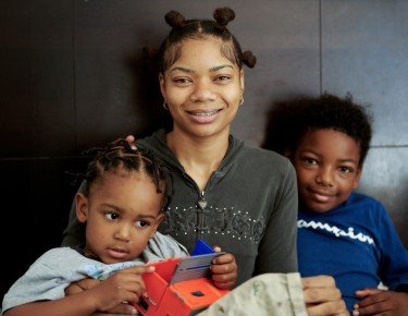 Young black woman smiling with her 2 sons